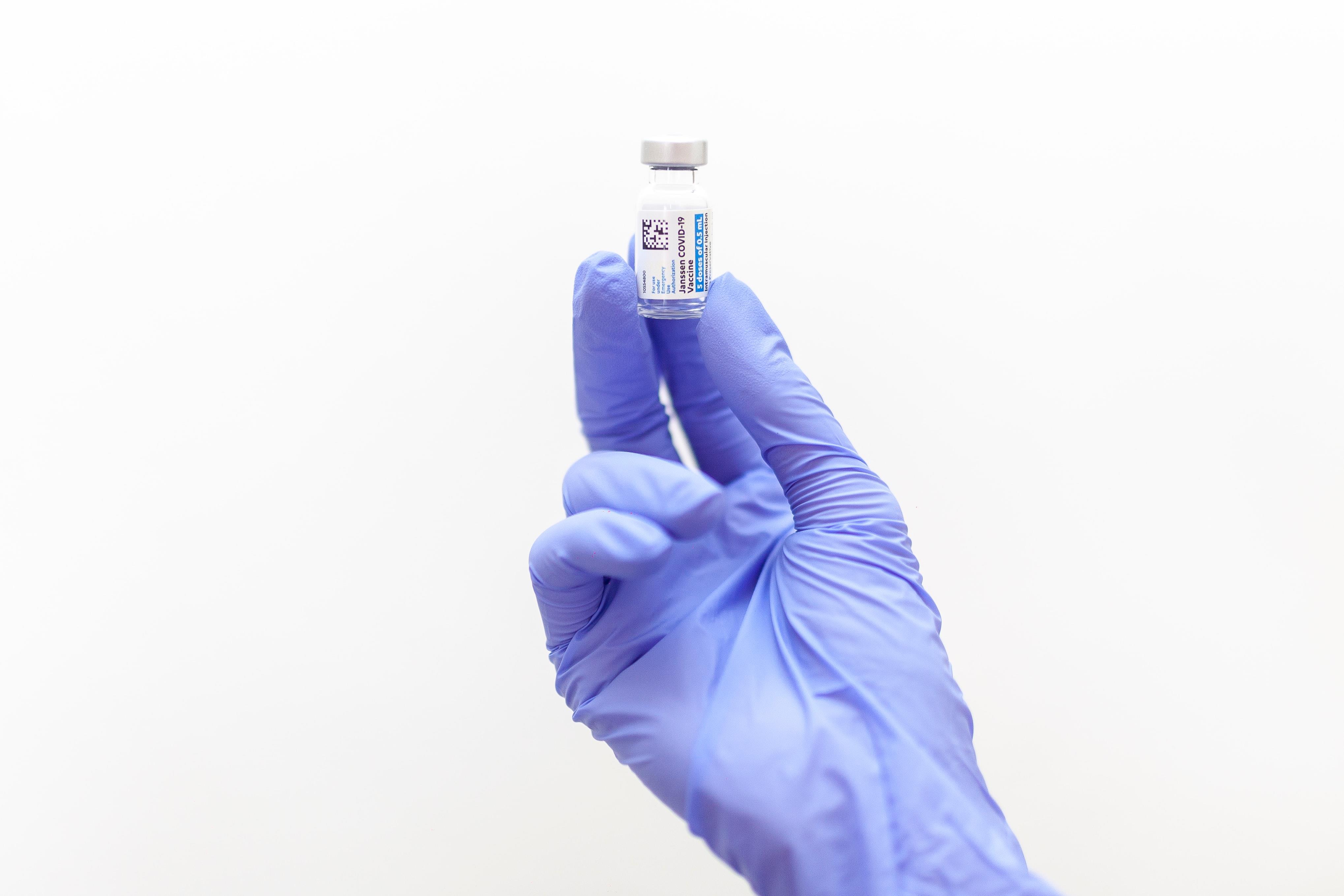 Bildet viser ein hand som holde opp ei vaksinedose i eit glas.