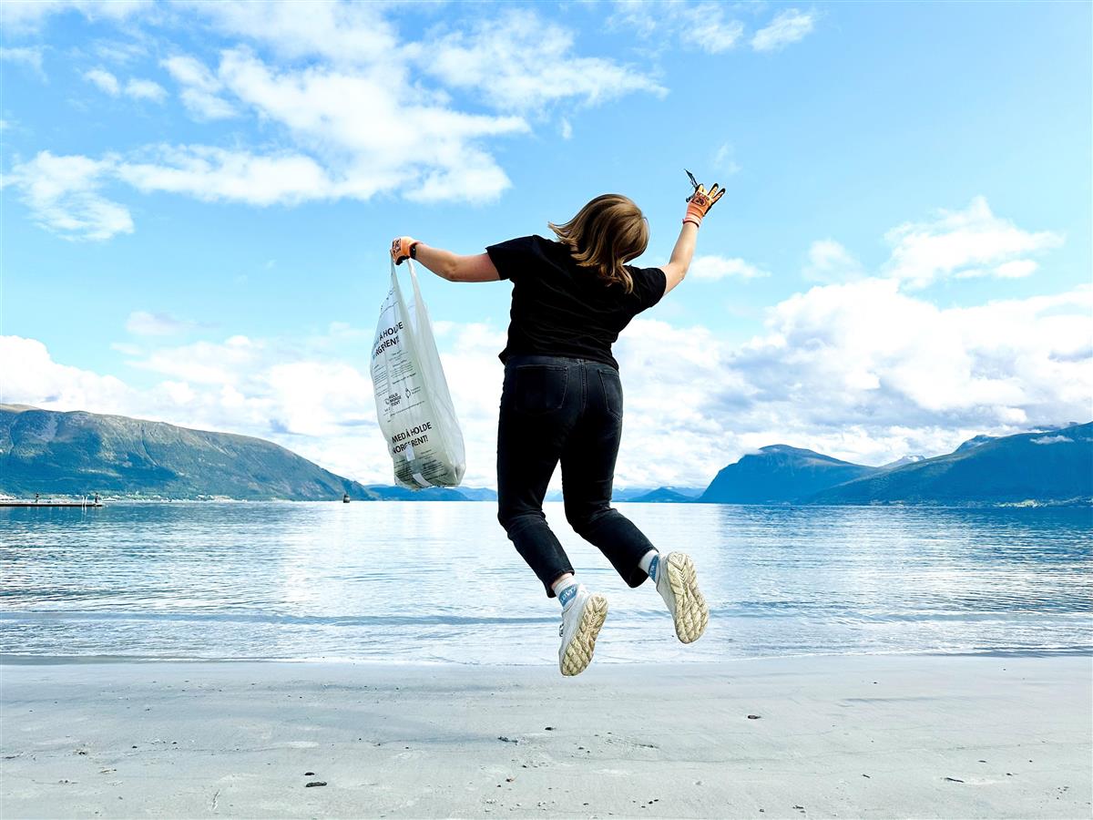 Bilde av ein person som hoppar med ein søppelpose i handa. - Klikk for stort bilete