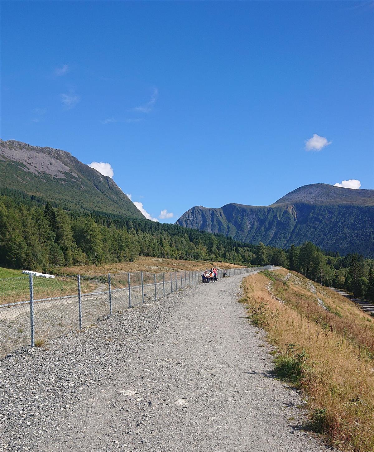 Fonnvernet den meste besøkte StikkUT turen i løpet av ​​​​​​sommarsesongen 2022 i Ørsta kommune. Bilde av grusvegen opp på fonnvernet mot skogen og fjella i nydeleg sommarver - Klikk for stort bilete